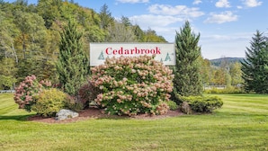 Un panneau indiquant l’entrée de Cedarbrook, avec un jardin bien entretenu et des arbres en arrière-plan.