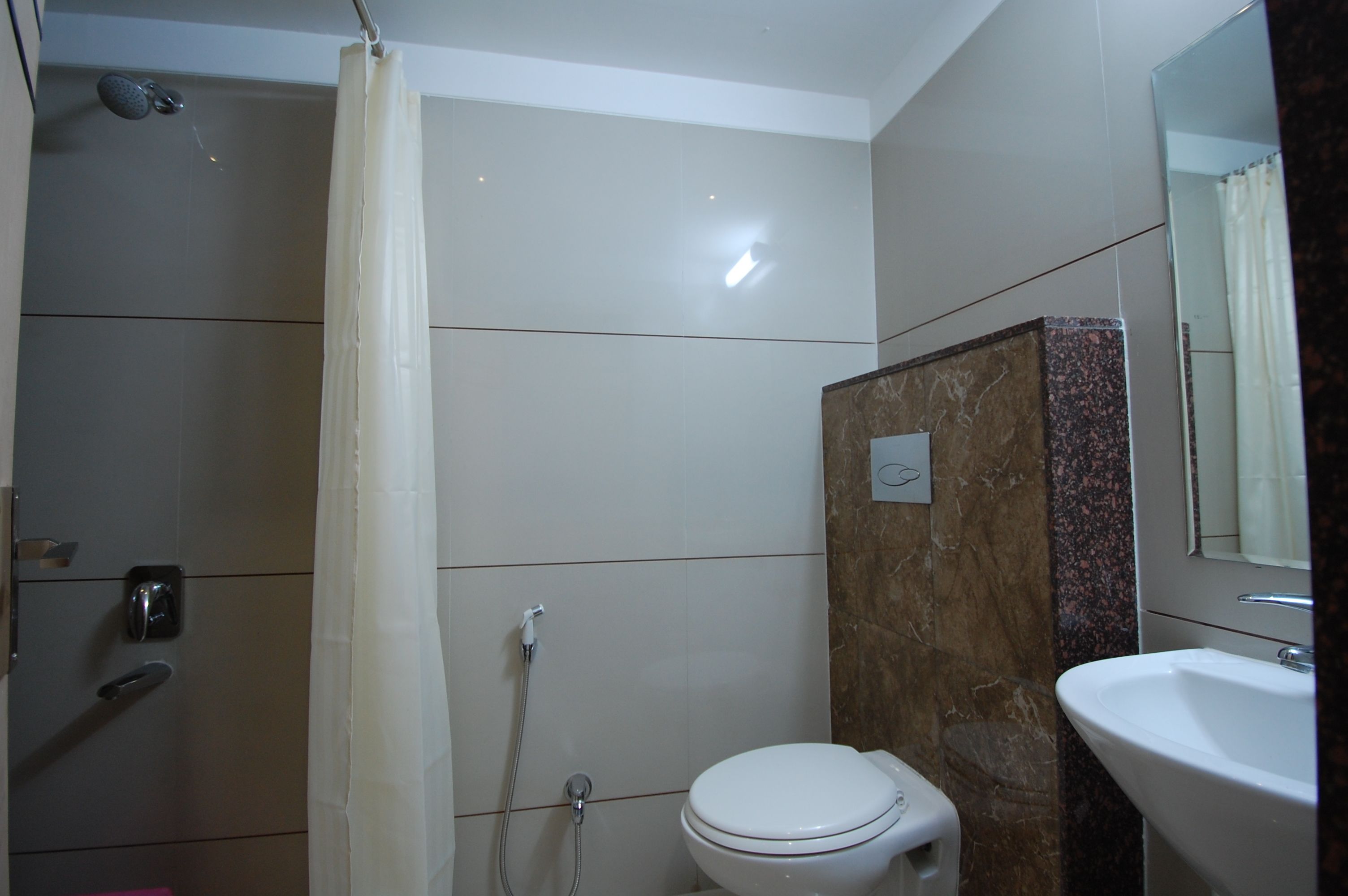 Une salle de bain avec douche, toilettes et lavabo.