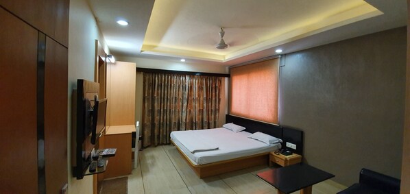 Una habitación de hotel moderna con una cama, un escritorio, un armario y un televisor.