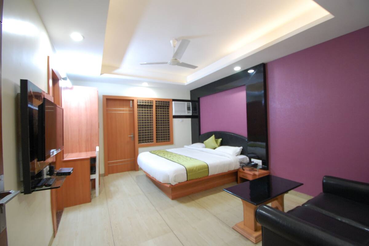Una habitación de hotel moderna con cama, escritorio, silla y televisor.