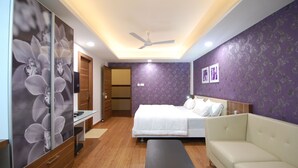 Quarto com cama, sofá, televisão e ventoinha no teto.