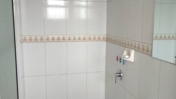 Un baño con baldosas blancas, una alfombra verde, un lavamanos y un espejo.