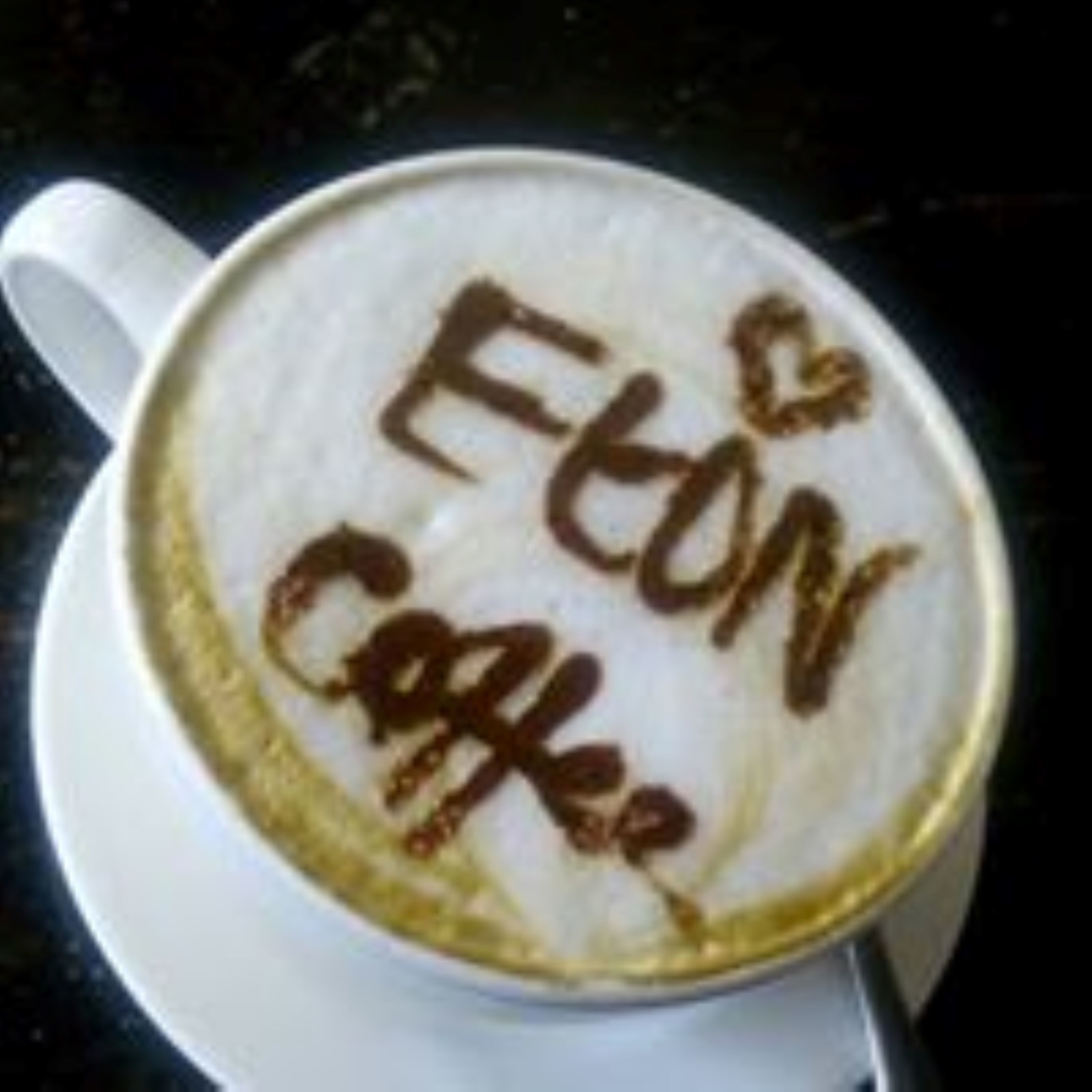 A cup of coffee with latte art spelling "Eton Cafe".
