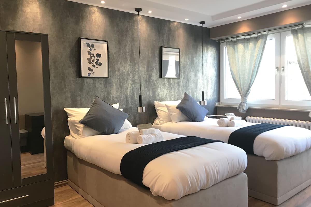 Quarto de hotel moderno com duas camas, um espelho grande, obras de arte e vista para o exterior.
