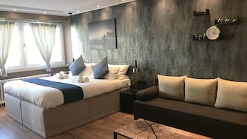 Un dormitorio moderno con cama, sofá, mesa de centro y un reloj en la pared.