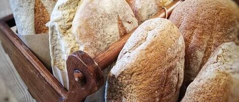 A wooden bread basket filled with various loaves of bread.