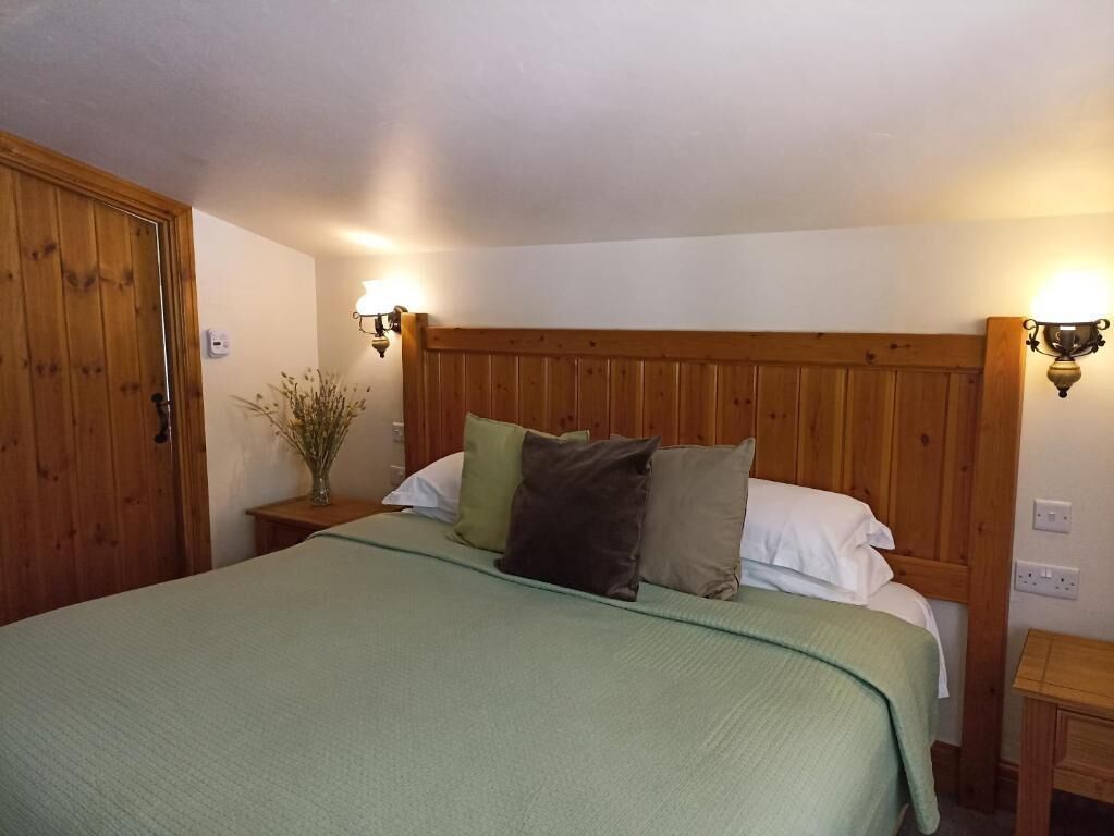 Une chambre à coucher avec une tête de lit en bois, un lit agrémenté de plusieurs oreillers, des lampes de chevet et une table de chevet.