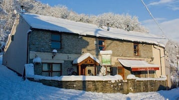 A stone building with a snow-covered roof and a wooden entrance.