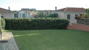 A residential area with a well-maintained lawn, stone pathway, and a stone wall.