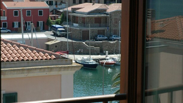 A view of a marina with boats docked, surrounded by buildings with red-tiled roofs.