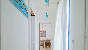 A hallway with a carpeted floor, a dining area with chairs and a table, and a blue door. - La Naca sul Mare (Nardò)