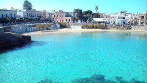 A coastal town with clear turquoise waters, rocky shoreline, and buildings along the beach. - La Naca sul Mare (Nardò)