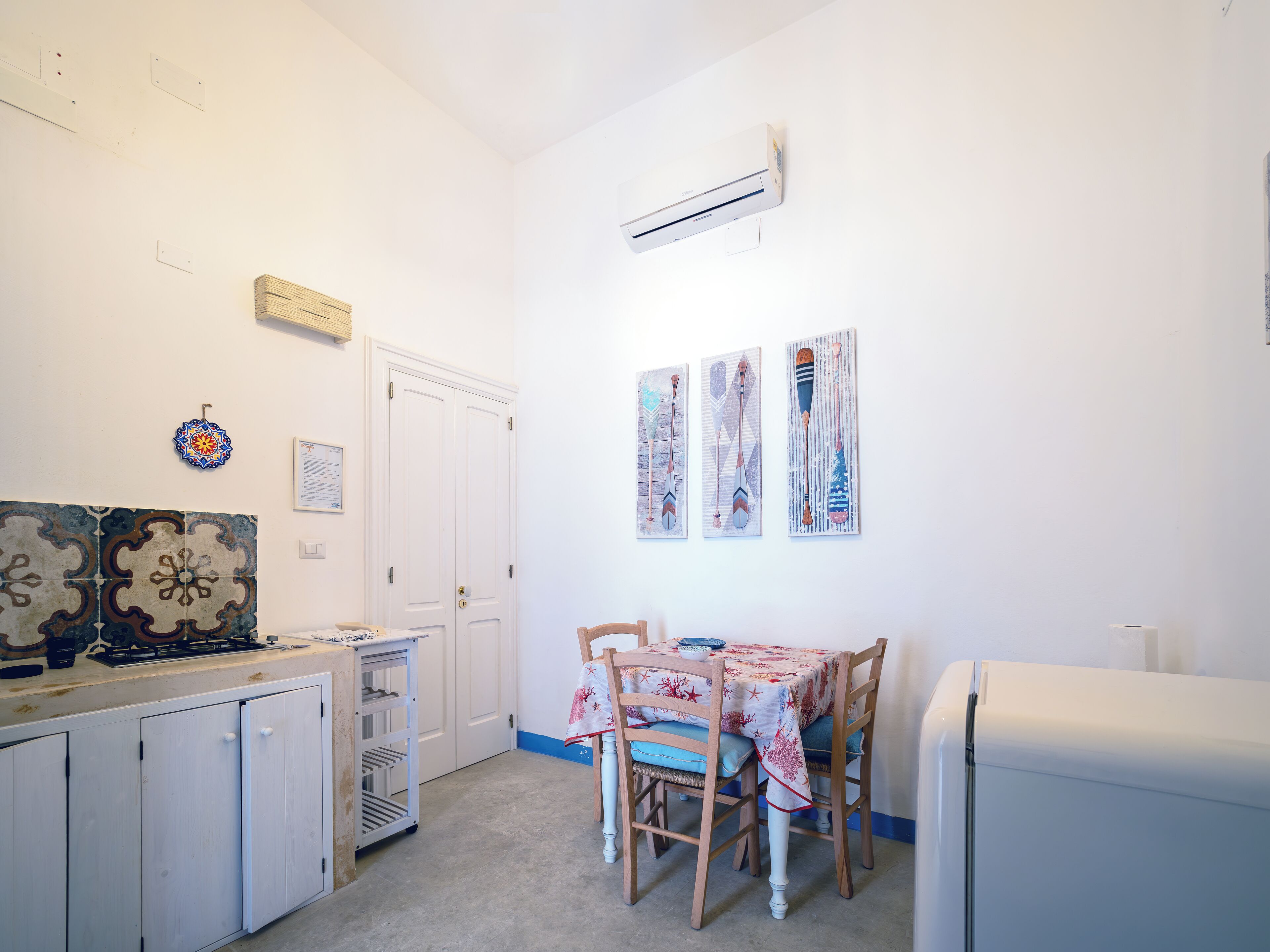 A compact kitchen with a dining table, white cabinets, and a refrigerator.