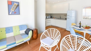 Een moderne keuken met witte kastjes, een witte koelkast en een eethoek met een tafel en stoelen.