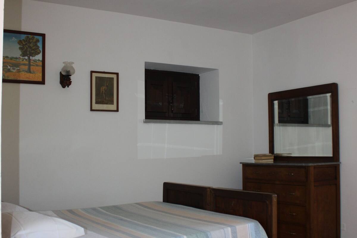 Ein Schlafzimmer mit einem Bett, einer Holzkommode und einem Spiegel.