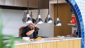 Una encimera de cocina con un chef preparando comida, luces colgantes en la cocina y un salpicadero de azulejos.