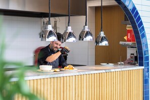 Una encimera de cocina con un chef preparando comida, luces colgantes en la cocina y un salpicadero de azulejos.