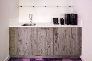 A modern kitchen with a stainless steel sink, a coffee machine, and a box with a black interior. - YOTEL Amsterdam (Amsterdam)