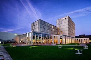 A modern hotel with a glass facade, outdoor seating area, and a well-maintained lawn. - YOTEL Amsterdam (Amsterdam)