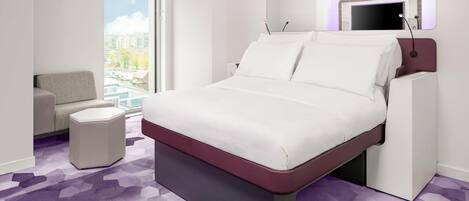 Ein modernes Hotelzimmer mit einem großen Bett, einer Sitzecke und Blick auf die Stadt.