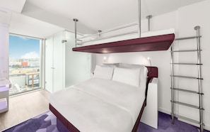 A modern hotel room with a large bed, a balcony, and a view of the city. - YOTEL Amsterdam (Amsterdam)