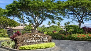 Naamplaatje voor Waikoloa Beach Villas, met een aangelegde omgeving met verschillende planten en bomen.