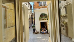A view through an open window of a narrow street with a restaurant named "KITCHEN" in the center. - The Suites at Central Split (Split)
