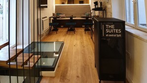 A modern interior with a staircase, a seating area with tables and chairs, and a sign for "THE SUITES at central Split". - The Suites at Central Split (Split)