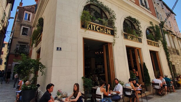 A building with a 'KITCHEN' sign, outdoor seating, and a 'BOKERIA' sign. - The Suites at Central Split (Split)