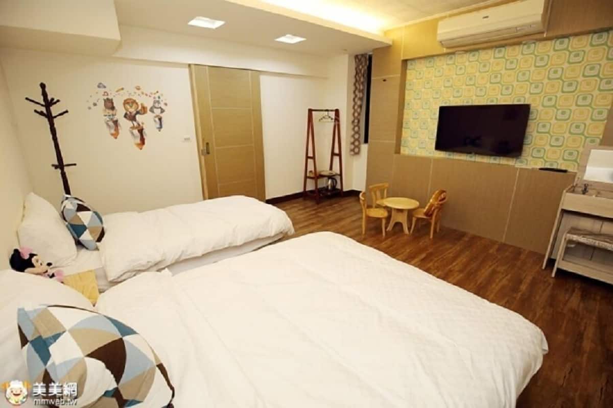 A hotel room with two beds, a TV, a small table, and a chair.