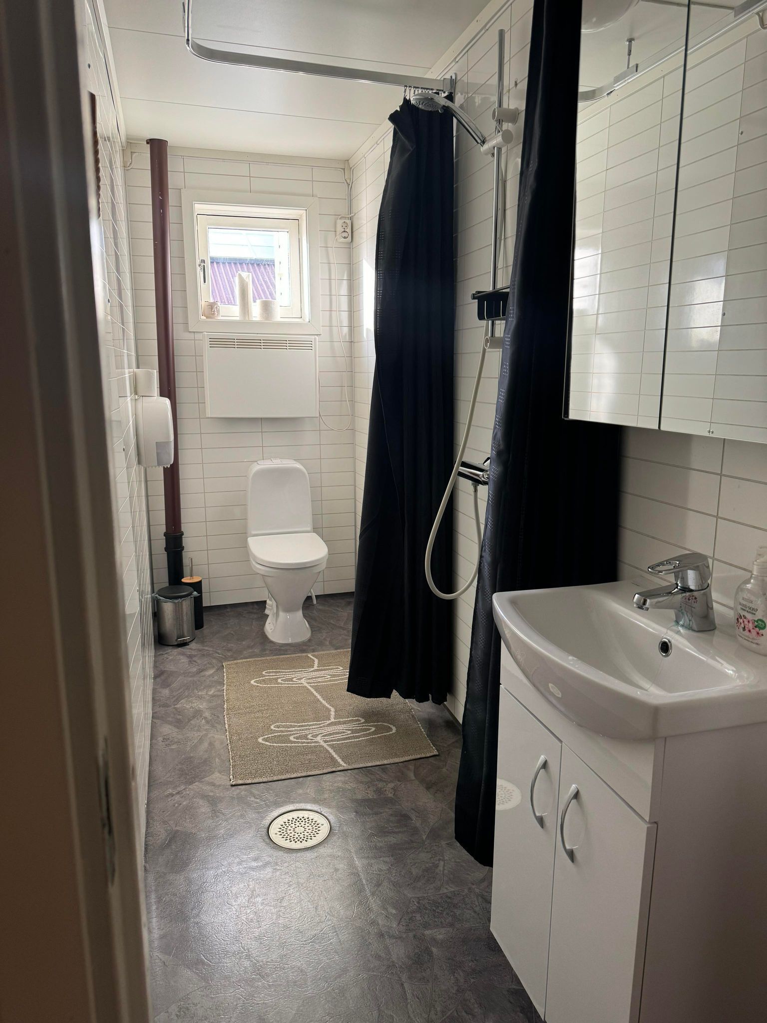 Une salle de bain avec des toilettes, un lavabo, une douche et une fenêtre.