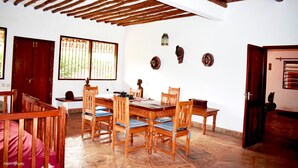 A dining area with wooden furniture and a tiled floor. - Fabio House (Diani Beach)