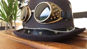 Um chapéu estilo steampunk com óculos de proteção e detalhe em corrente.