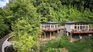 Dos cabañas elevadas con terrazas, rodeadas de un bosque denso.