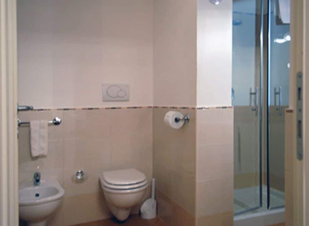 A bathroom with a toilet, bidet, and a glass-enclosed shower area.