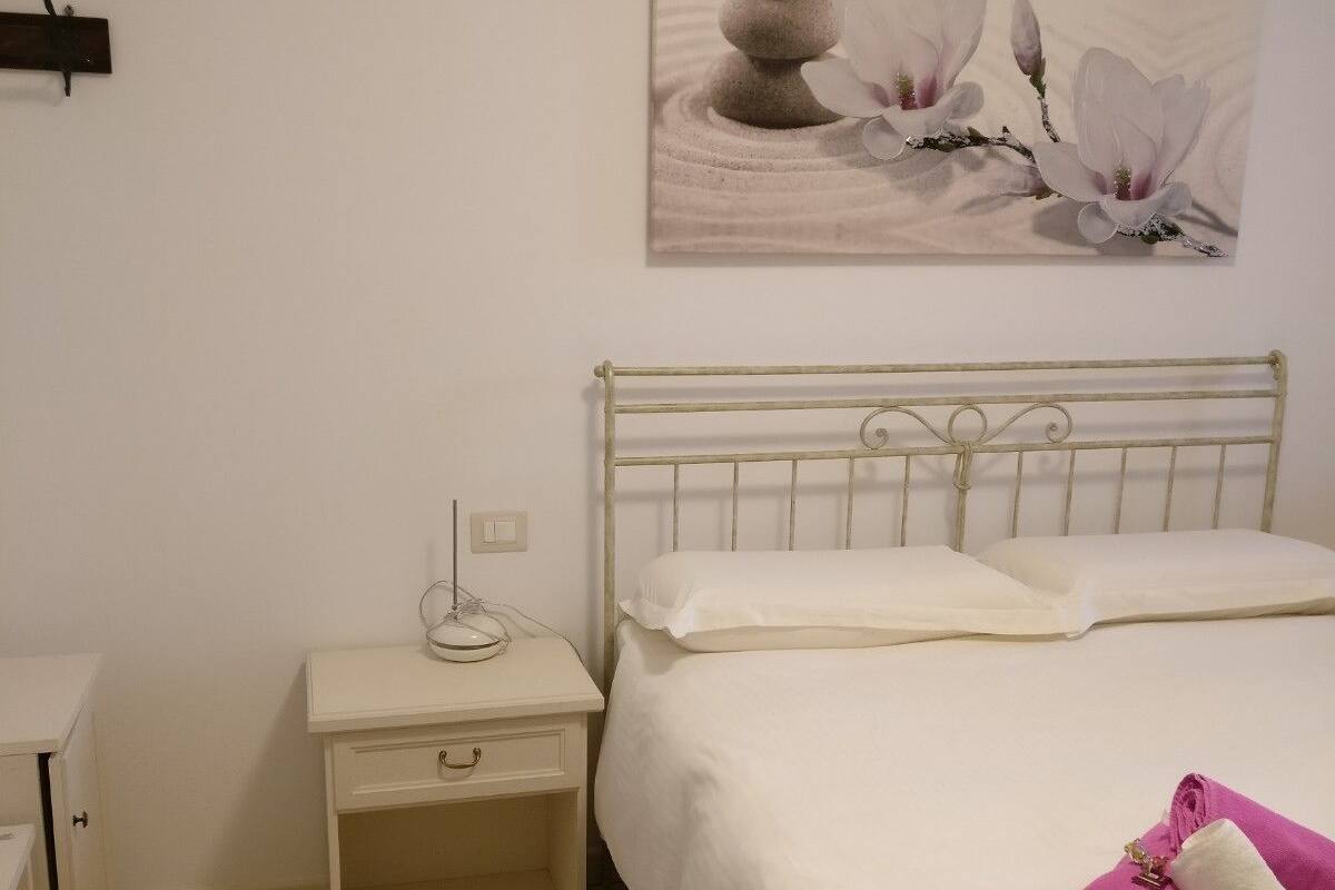 Ein Schlafzimmer mit einem Bett, einem Nachttisch und einem Wandbild.