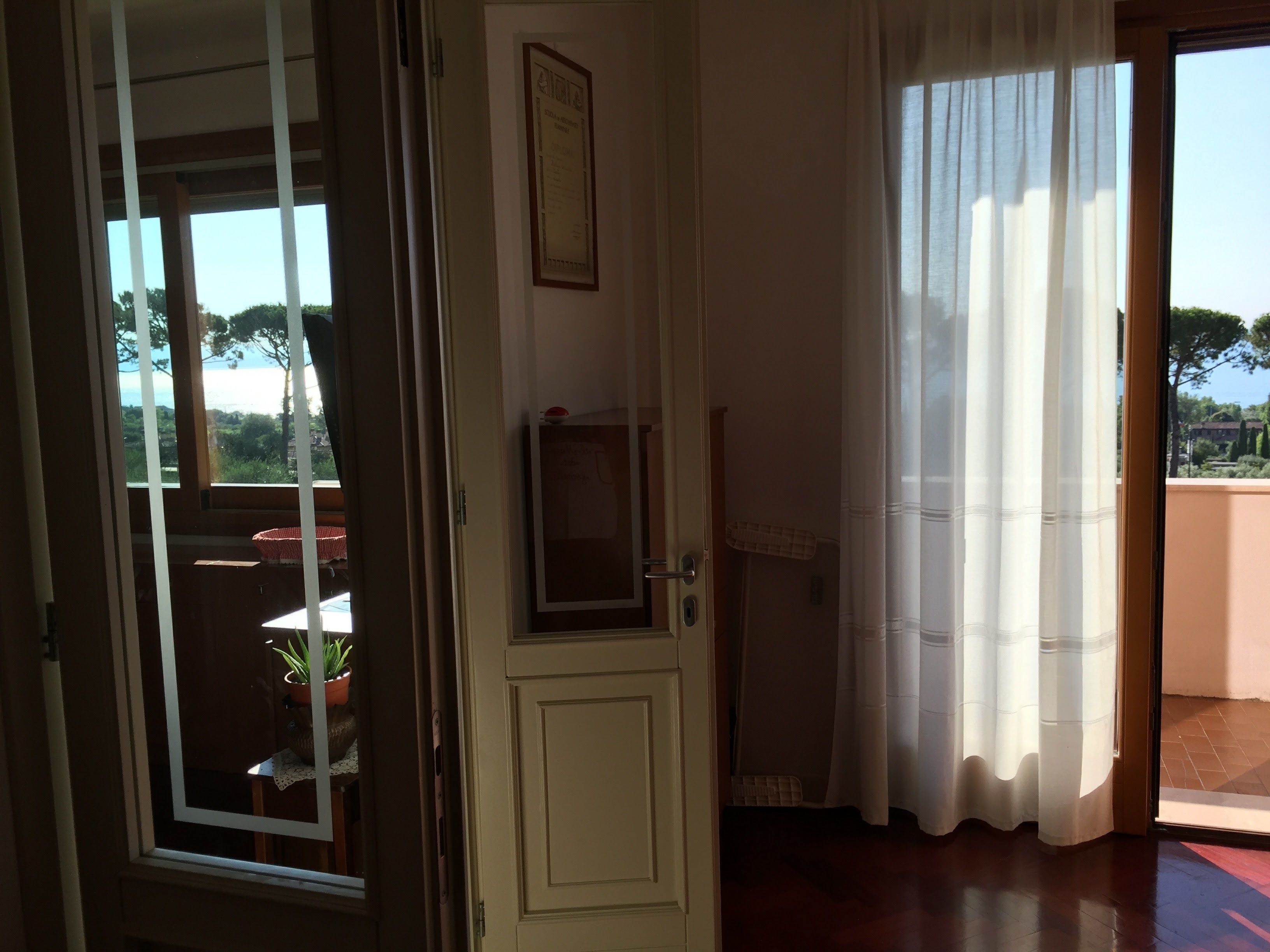 A room with a wooden door, a small window, and a view of greenery outside.