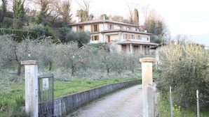 Une maison à deux étages avec une allée pavée menant à une entrée fermée par un portail.