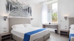 A modern hotel room with a large bed, a window with a view, and a unique wall art piece. - Toledo one (Naples)