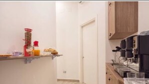 A narrow kitchen with a coffee machine, a shelf with kitchen items, and a door leading to another room. - Toledo one (Naples)