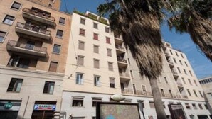 A multi-story building with balconies, a parking garage sign, and palm trees. - Toledo one (Naples)