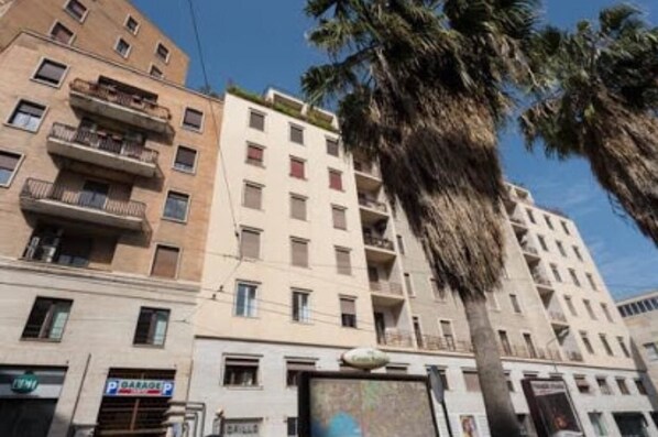 Un edificio de varios pisos con balcones, un letrero de estacionamiento y palmeras.