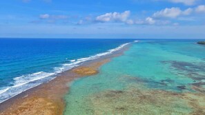 An aerial view of a beach with clear turquoise waters and a sandy shoreline.