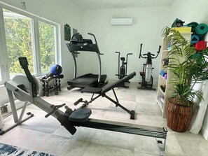 Kotikuntosali, jossa on soutulaite, kuntopyörä ja juoksumatto.