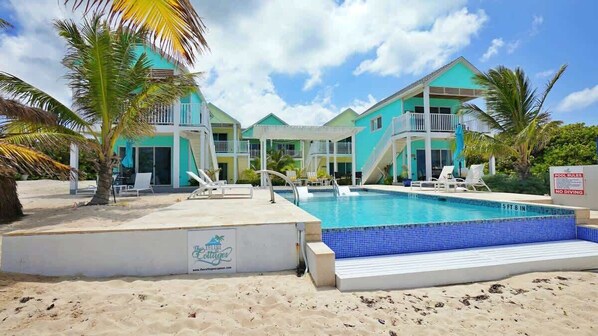A resort with a swimming pool, multiple balconies, and a beach area.