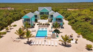 A resort with a pool, multiple guest rooms, and a beach area.