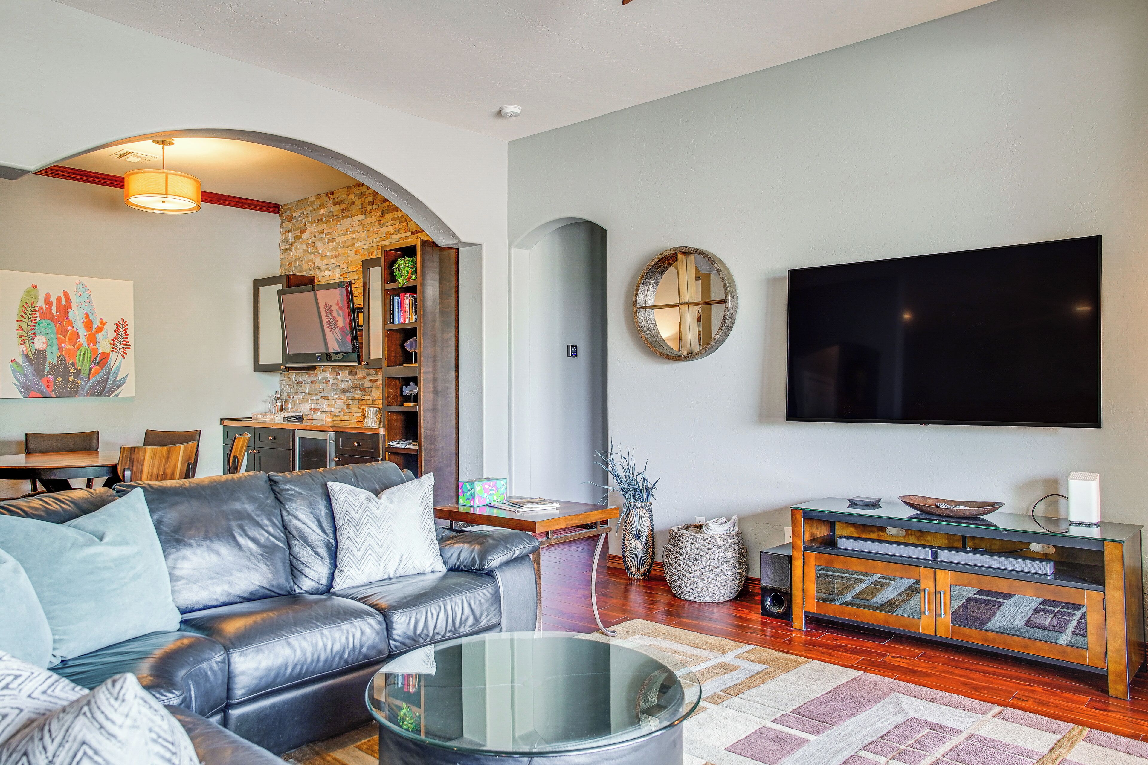 Ein modernes Wohnzimmer mit Ledersofa, Glastisch, Flachbildfernseher und Bücherregal.