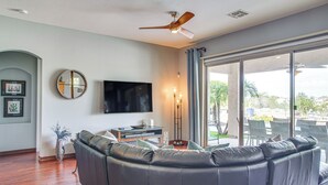 Ein Wohnzimmer mit einem großen Ledersofa, einem flachbildfernseher an der Wand und einem Deckenventilator.