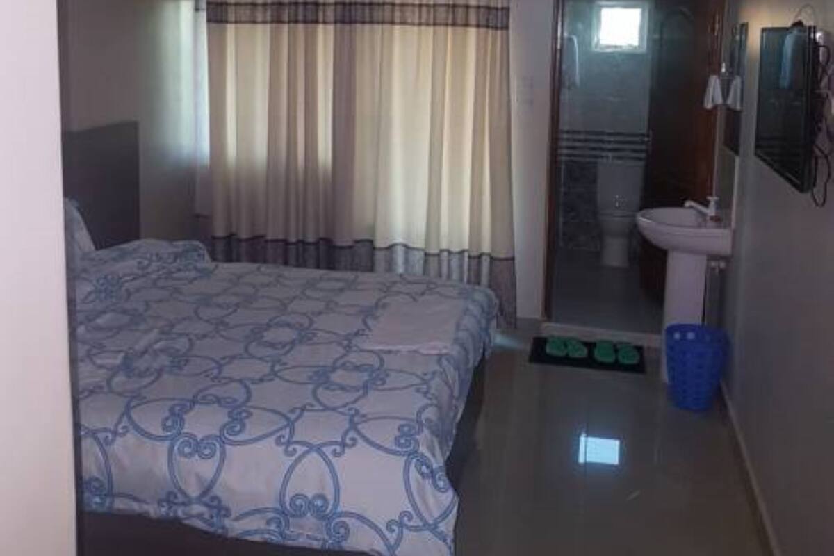 A hotel room with a bed, a bathroom with a sink, and a mirror.