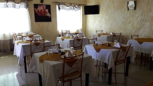 Un espace repas avec des tables dressées, des chaises et une horloge au mur.